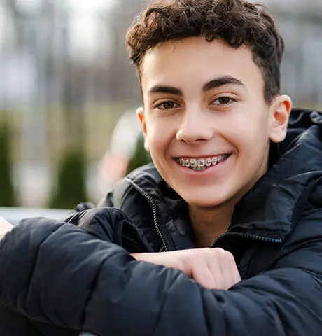 Teen boy with braces smiles.